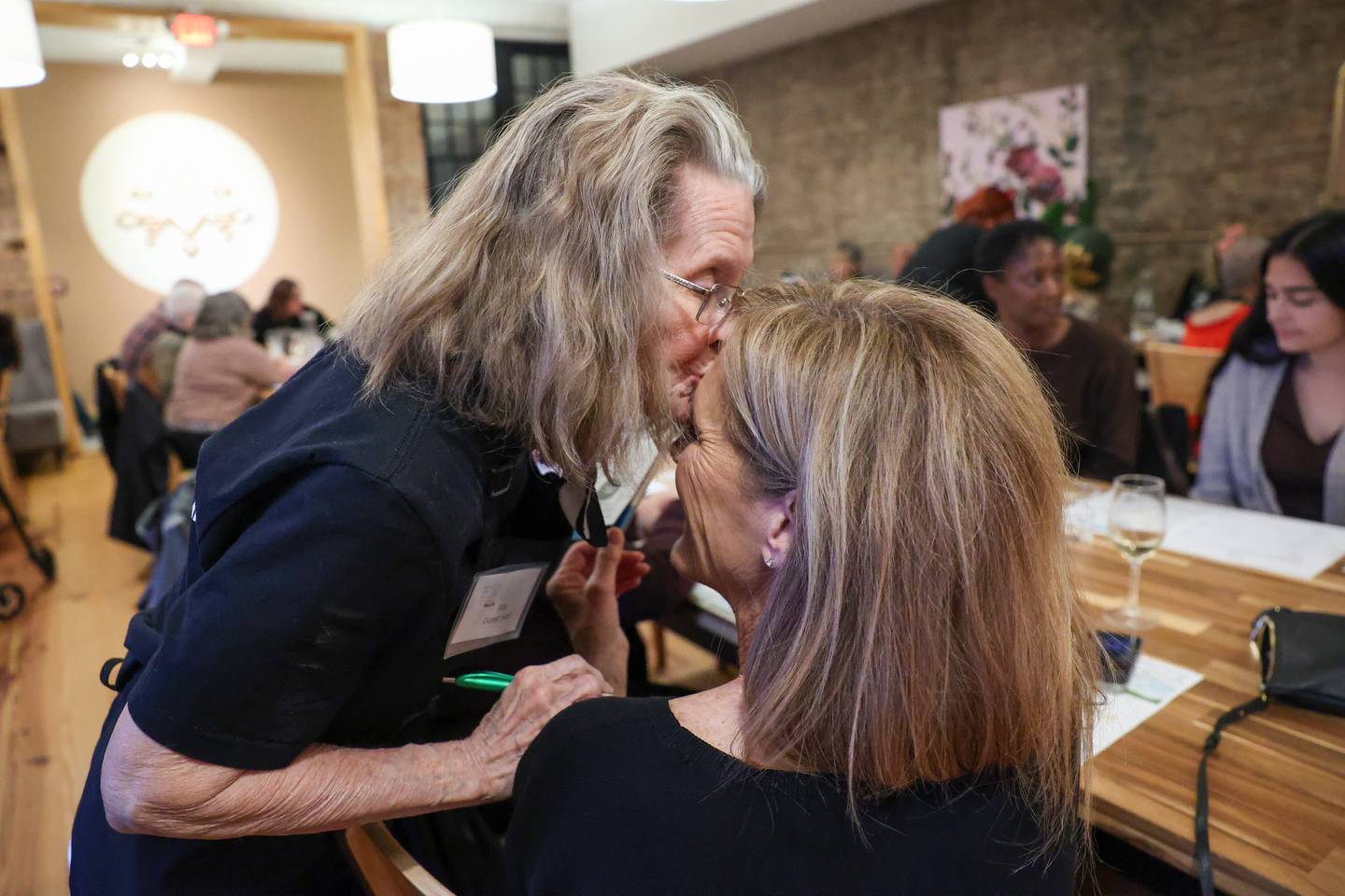 Guest host Rita Blanchette, left, plants a smooch on the forehead of Renee Schnell, of Kankakee, after taking her order during a Mistaken Orders program event called Sip Happens, hosted by nonprofit Our Aging Services and MCA Senior Adult Day Center at Stefari West Avenue on Nov. 18, 2025.