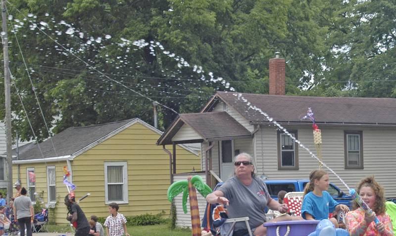 An employee of American Leak Detection cools the crowd during the Petunia Festival parade Sunday,  July 6,  2025.