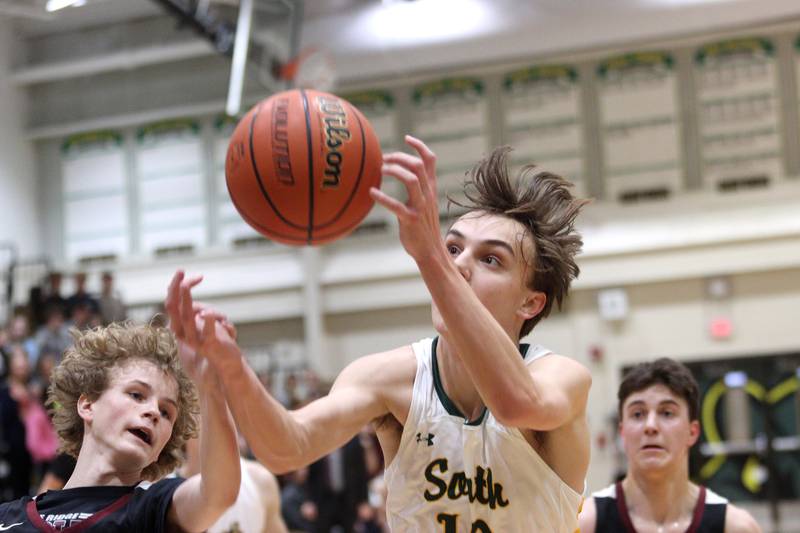 Prairie Ridge’s John Fuery, left, and Crystal Lake South’s Cameron Miller battle for the ball in varsity boys basketball at Crystal Lake South Friday night.