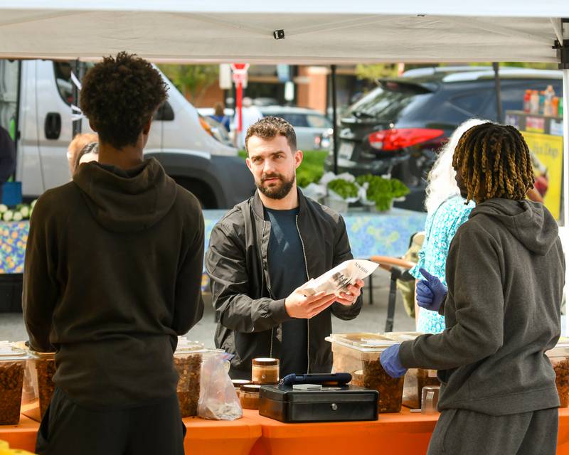 Carter Beebe of Downers Grove buys some nuts from Nuts to Go on Saturday May 31, 2025, during the Farmers Market held at the Main Street train station in Downers Grove.