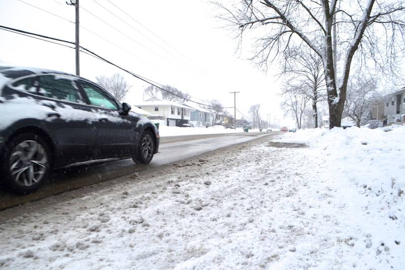 A car drives along 135th Street in Romeoville as snow falls on Thursday, Feb. 4, 2021. The National Weather Service calls for more snow and low temperatures throughout the weekend.