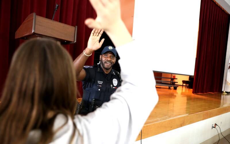 Geneva Police Officer Quantrell Priest high-fives a student after giving a presentation about computer safety to sixth-graders at Geneva Middle School North.