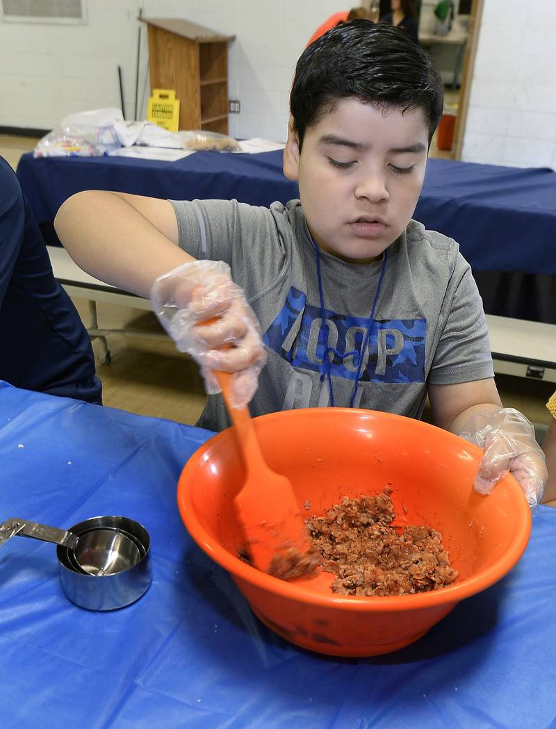 Mateo Orozco stirs up beans as preparation for layered bean dip on Friday, June 30, 2023, at Northlawn Junior High in Streator during the Illinois Junior Chefs class.