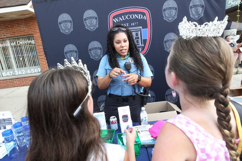 Tanisha Thomas, Wauconda Police Dept. community service officer, talks with Violet Niziolek, 11, of Wauconda (Jr. Miss Wauconda Area 2022) and Arabella Porter, 10, of Crystal Lake (LCSP Ambassador) during National Night Out on Main Street on Tuesday, August 1st in Wauconda.  
Photo by Candace H. Johnson for Shaw Local News Network.