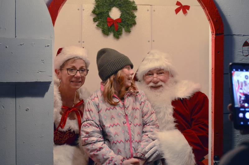Elizabeth Pearce, 10, of Polo, smiles at Santa Claus as she poses for a photo with him and Mrs. Claus on Saturday, Dec. 2, 2023. Santa and Mrs. Claus visited Paul's Park in Polo to hear kids wish lists as part of the fifth annual Polo Christmas Festival.