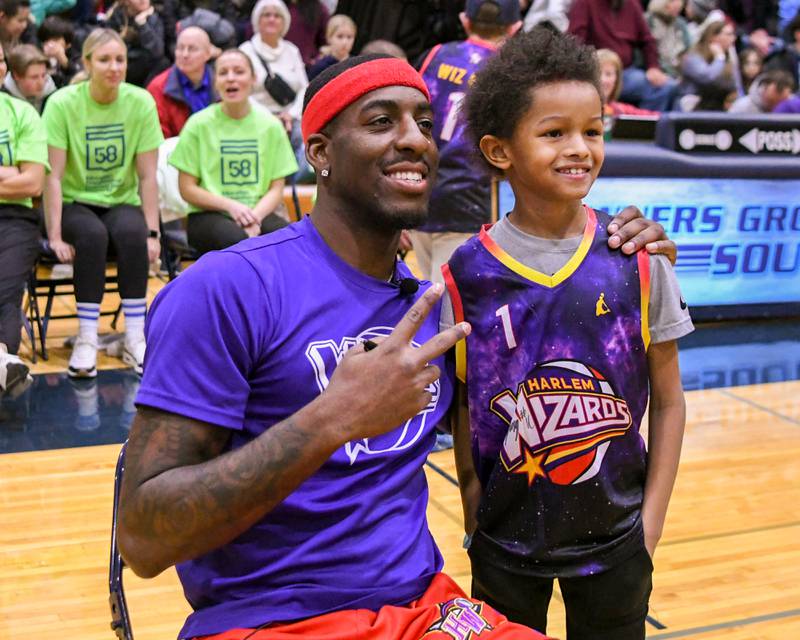Jace Rice, 8, of Downers Grove poses for a photo with a  Harlem Wizard player Dragon  on Sunday Jan. 19, 2025, before the start of the game held at Downers Grove South High School.