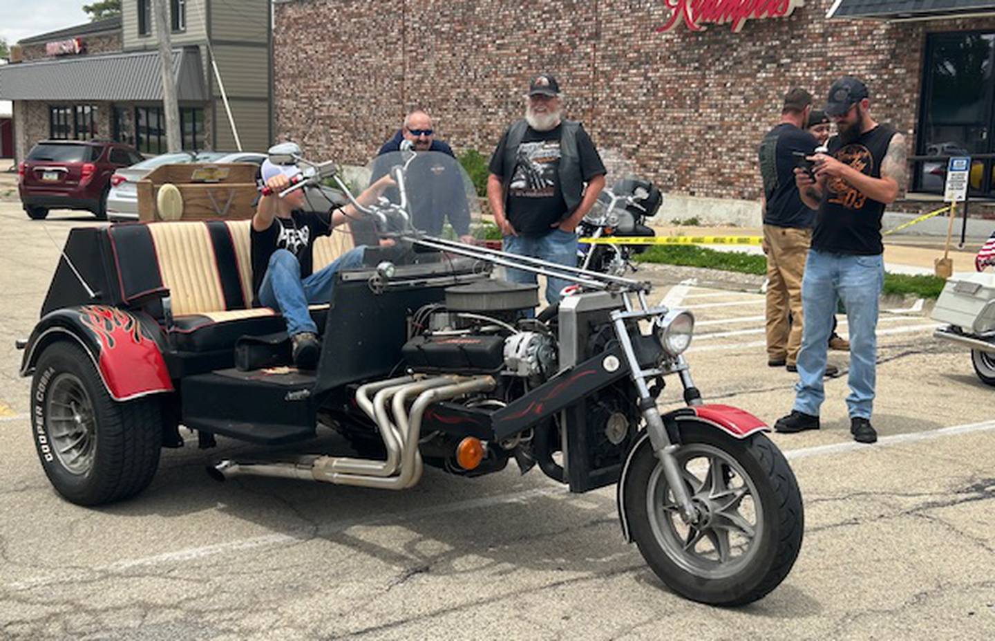 Zander Halverson, (seated) checks out a 1987 Cobra Speedster at the Blessing of the Bikes in downtown Fulton on Sunday, June 2, 2024. The bike is owned by Fulton resident Bud Rose (standing second from left).
