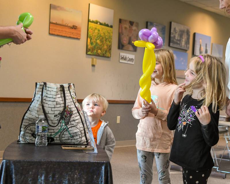 Siblings Mac McLaughlin 2, Nora McLaughlin, 7, and Josie McLaughlin,5, of DeKalb watches as they get balloon creations done on Sunday Oct. 12, 2025, during the DeKalb County 4-H carnival held at the DeKalb Farm Bureau in Sycamore.