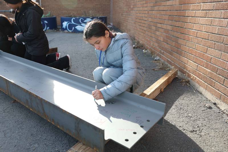 6th grader Maya Zambrano signs a beam that will be use in the construction of the new Hufford Junior High School on Friday, Dec. 13, 2024 in Joliet.
