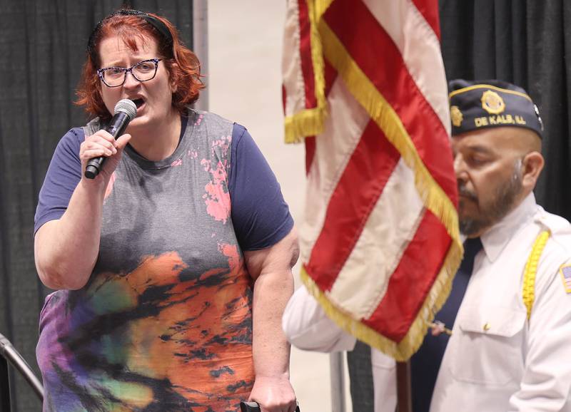 Diana Johnson sings "The Star-Spangled Banner," as Manny Olalde from the DeKalb American Legion holds the flag Thursday, April 23, 2026, to kick off the DeKalb Chamber of Commerce Local Showcase in the Convocation Center at Northern Illinois University in DeKalb.