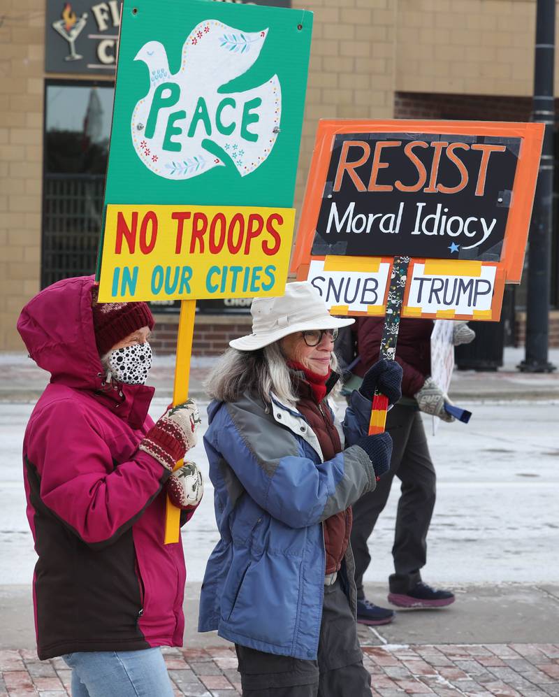 Protesters carry signs Tuesday, Jan. 20, 2026, at Memorial Park on the corner of First Street and Lincoln Highway in DeKalb as part of a national Free America Walkout. The group is protesting what they perceive as an escalating fascist threat under President Donald Trump and his administration.