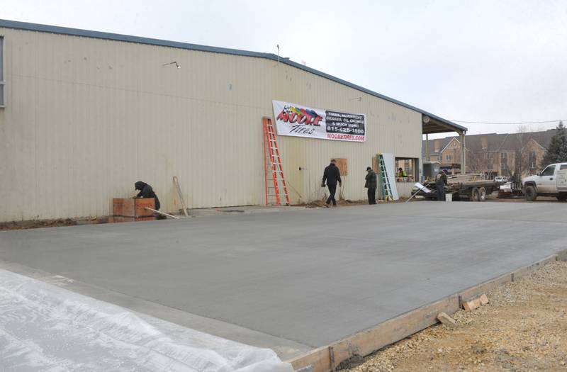 Kyle Moore and Todd Billings secure a Moore Tires banner to the business' new location on Tuesday, Feb. 6, 2024.