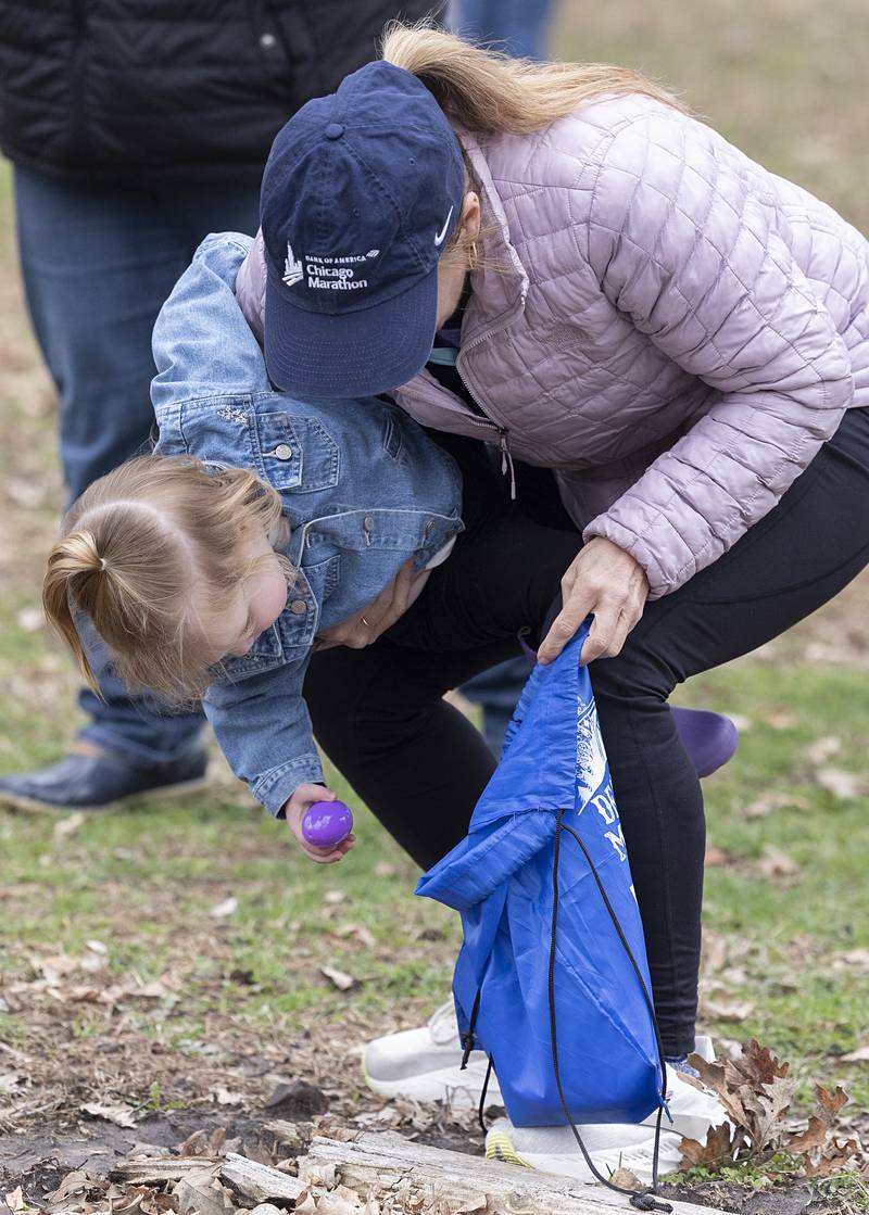 Sandy Lightner helps out Maren Brinkmeier, 2, gobble up an egg Saturday, April 4, 2026, during the Amboy Easter egg hunt.