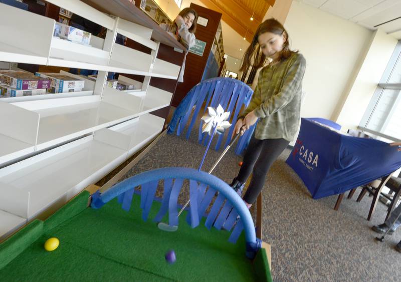 Nine-year-old Aria Brossett of Yorkville skillfully hits a shot under the CASA arch hazard during a Mini Golf Fundraiser at the library, hosted by The Friends of the Yorkville Public Library on Sunday, April 3, 2022.