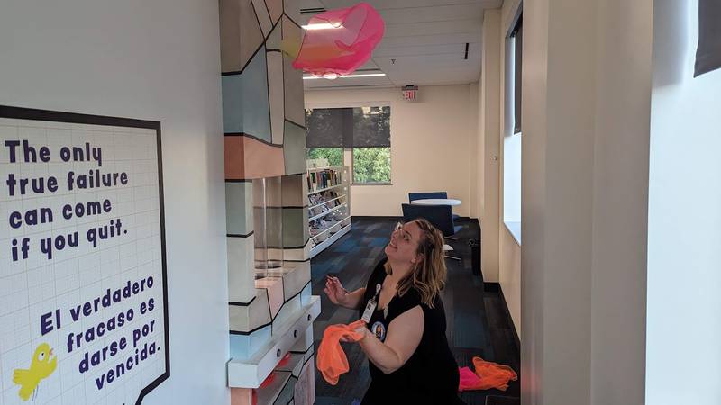 Mallory Hewlett, communications manager at the Joliet Public Library, makes scarves "fly" on Wednesday, June 21, 2023, at the Ottawa Street branch of the Joliet Public Library. The scarf play is part of the “The Questioneers: Read. Question. Think. PLAY!” exhibit based on the Questioneers book series authored by Andrea Beaty and illustrated by David Roberts. The traveling, interactive exhibit is available during library hours through July 29.