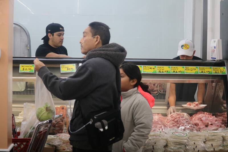 Customers walk by as DeKalb Fresh Market staff work the fresh meat counter during the store's grand opening held Tuesday, Nov. 21, 2023.