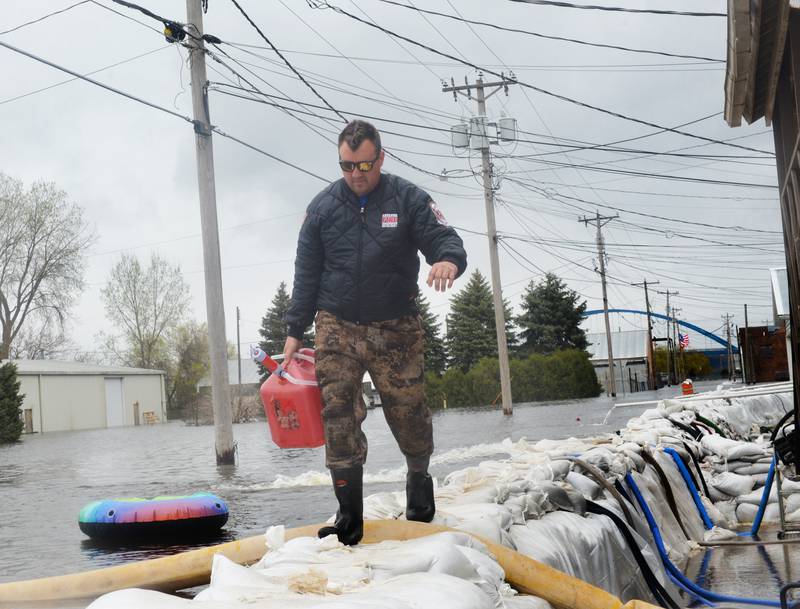 Jacob Helms, a volunteer firefighter with the Savanna Fire Department, walks on top of the sandbag wall as he refuels pumps just west of Main Street in the city's downtown Sunday. Firefighters along with volunteers and inmates from Kewanee and East Moline, constructed the wall with 47,000 sand bags in anticipation of river levels rising past the 21-foot mark.