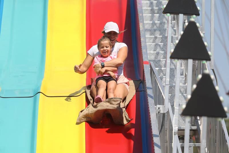 Becky Quijano, of Frankfort, rides down the slide with her daughter Quinn, 4-years-old, at the Will County Fair on Sunday, August 25, 2024 in Peotone.