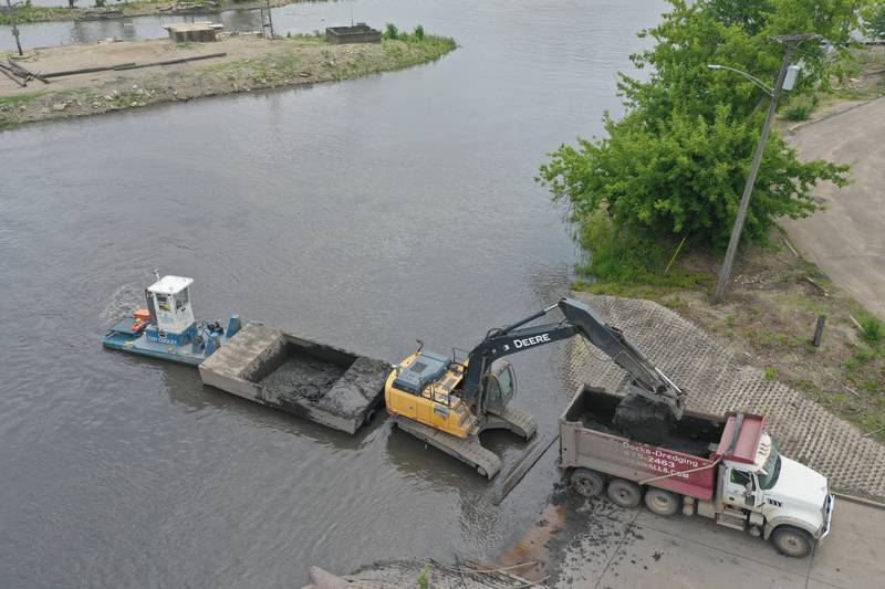 Crews with Superior Sea Walls and Docks, dredge the Henry Marina on Monday, June 9, 2025 in Henry. The operation involves using an excavator on a flat barge while removing silt from the water and placing it into a smaller barge that is pushed to the shoreline by a small tug boat. 
An additional excavator will move the silt onto a tandem truck and then moved off-site. The trucks are dumping the material on a city farm located north of town. 
Once completed the Henry Yacht Club will begin installation of replacement docks.