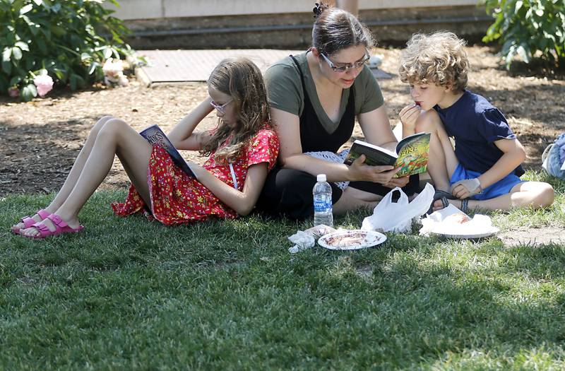 Genevieve, 8, Jenny, and Ben Karl, 8, read books Tuesday, June 20, 2023, at a Summer Woodstock Farmers Market around the Historic Woodstock Square. People were able to shop from over 40 of their favorite farms & producers for in-season food fresh produce, dairy, meats, breads, baked goods, spices, herbs, pasta, flowers and more.