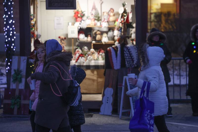 A family walks past one of several vendors along Veterans Parkway at New Lenox’s Christmas in the Commons.