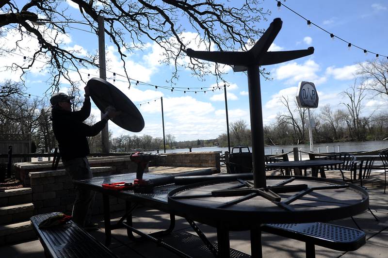 Mike Haber of the Broken Oar, 614 Rawson Bridge Road in Port Barrington, flips a table top Wednesday, May 4, 2022, as he prepares the outdoor patio for the upcoming summer boating season.