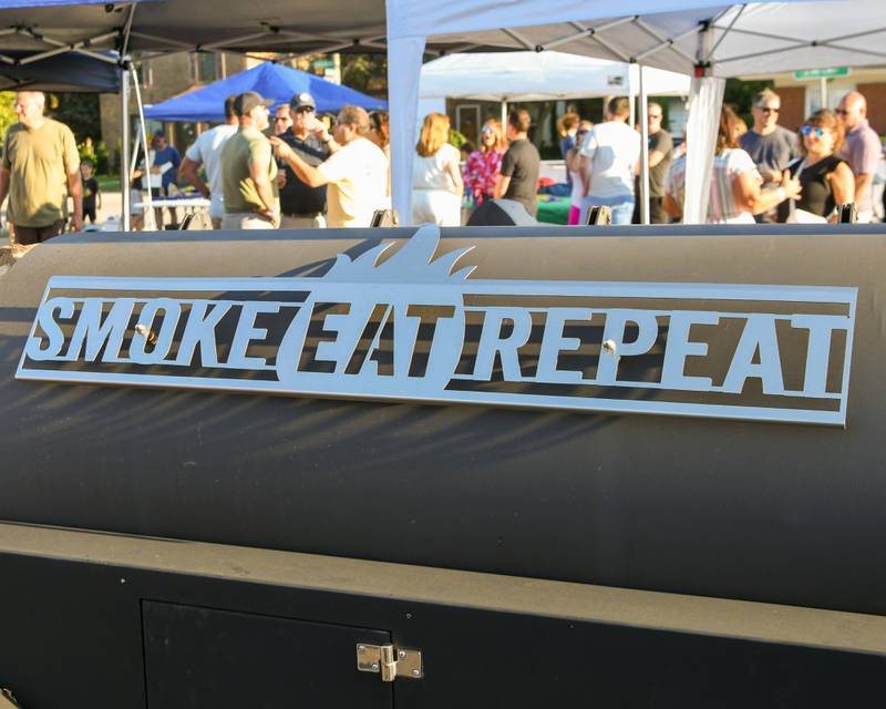 Back of a smoker at the Cue for a Cause event reads Smoke Eat Repeat held on Sunday Sep. 1, 2024, in downtown Elmhurst.