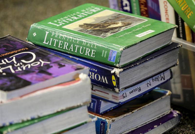 Several textbooks sit piled in Ryan Quigley's office Tuesday, May 21, 2019, at Joliet Catholic Academy in Joliet, Ill.