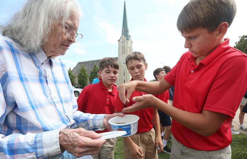(From left) Nancy Maze hands wildflower seeds to Oliver Schaeffer, Beau Maggi and Leo Gillan on Friday Aug. 29, 2025 at Academy of Saint Carlo Acutis in Peru. Maze taught students how to plant wildflower seeds and native prairie flowers. Some of the types of seeds included purple poppy mallow, blue flax, black eyed susan and milkweed. The Peru Historical Society assisted with the seed planting. Debo Ace Hardware also donated supplies.