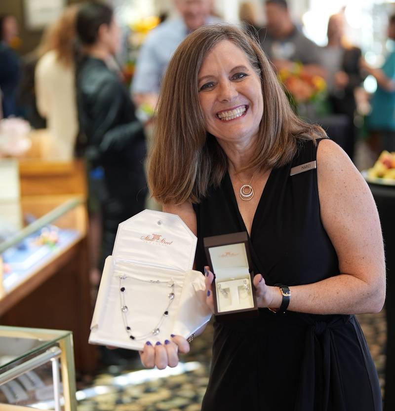 State Street Jewelers team member Marci Sterkel showcases two jewelry raffle prizes Sept. 25, 2025 during a party following the ribbon cutting for the Geneva store's 40th anniversary. Proceeds from the raffle benefited a local nonprofit, Fox Valley Food for Health.