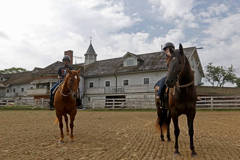 Richard Taylor-Terry, 11, and Joseph Birong, 6, ride Danta and Hunter, both retired Medieval Times horses, Friday July, 8, 2022, at the R Double J Ranch, 2800 Derby Lane, in McHenry. The R Double J Ranch recently got the contract to operate this equine facility from McHenry with the goal of making it more of a community-centric center and make learning about horses and riding open to all.