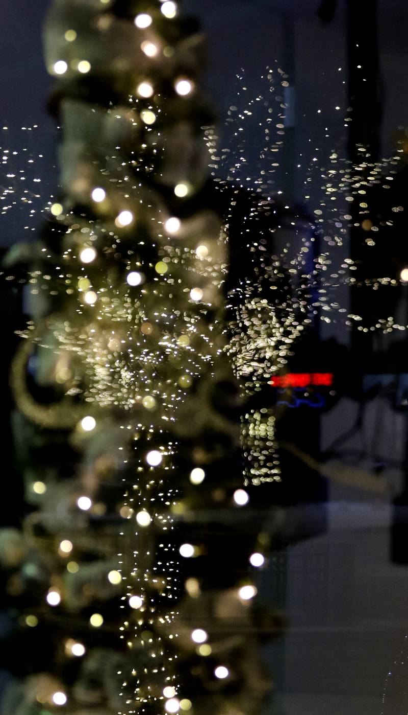 Holiday lights reflected in a window during Crystal Lake's Luminary Nights on Thursday, Dec. 19, 2024, in downtown Crystal Lake. The snowy night featured sidewalks lite luminaries, holiday shopping and a visit to the Santa House.