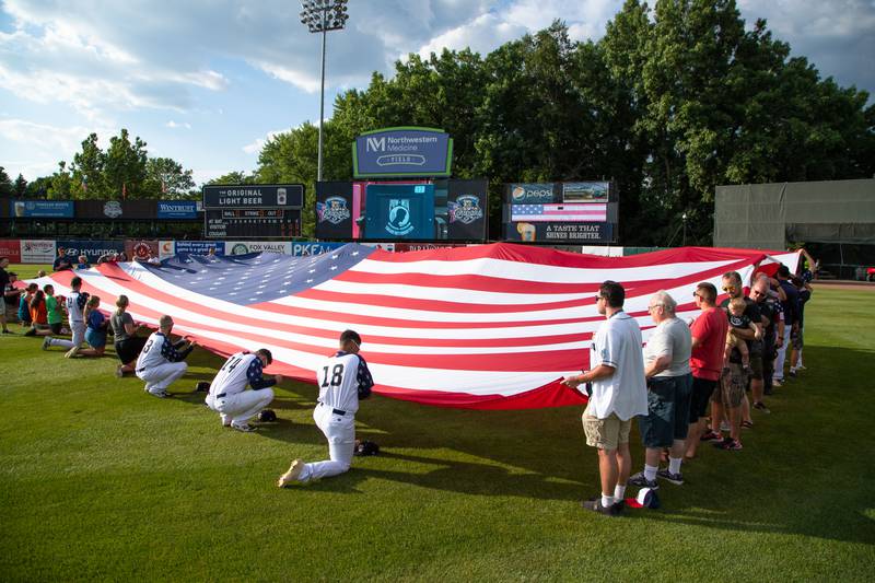 Players, fans, and veterans hold the American Flag on the Kane County Cougar's Military Appreciation Night on Saturday, July 2, 2022