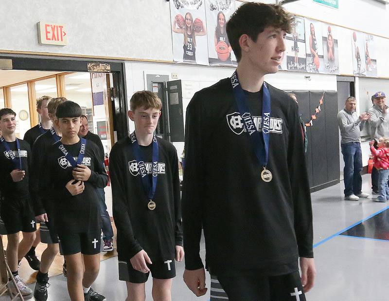 Members of the Mendota Holy Cross eighth-grade boys basketball team enter the gymnasium for a reception on Tuesday, Feb. 20, 2024 at Holy Cross School. The team beat Pana Sacred Heart 41-33 to win the IESA Class 1A State championship.