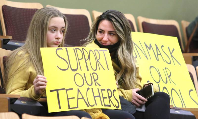 Sycamore sixth grade student Ava Rowland holds a sign asking for support for teachers with her mom Allie before the start of the Sycamore District 427 school board meeting Tuesday, Feb. 8, 2022, at Sycamore High School. Despite most of the attendees wearing masks the meeting was still halted and switched to a virtual format at a new location after School Board President Jim Dombeck said several maskless individuals refused to comply with districts instruction to wear a face covering.