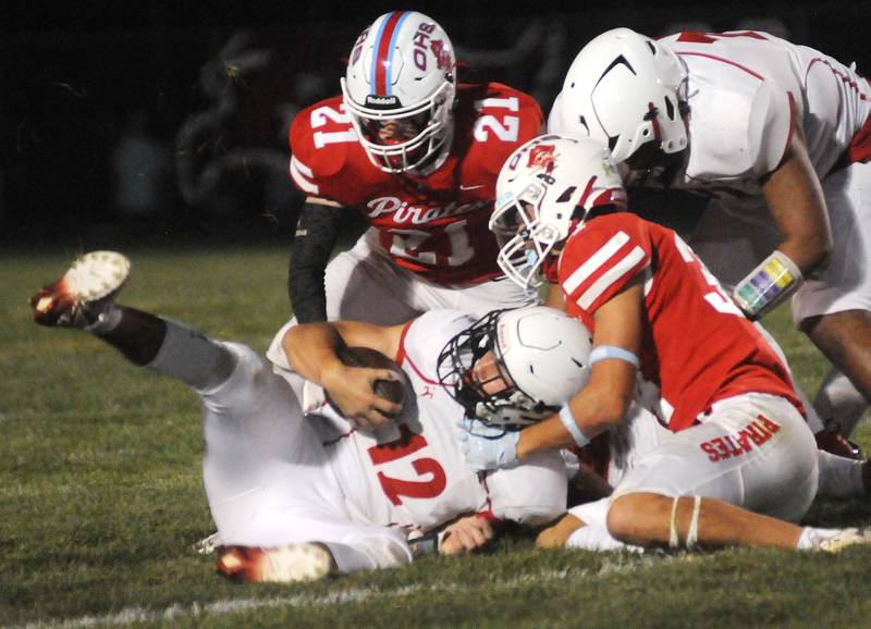 Ottawa teammates Garrett Couples (21) and Tyce Kubiak (34) tackle Streator quarterback Christian Benning at King Field on Friday, Sept. 1, 2023.