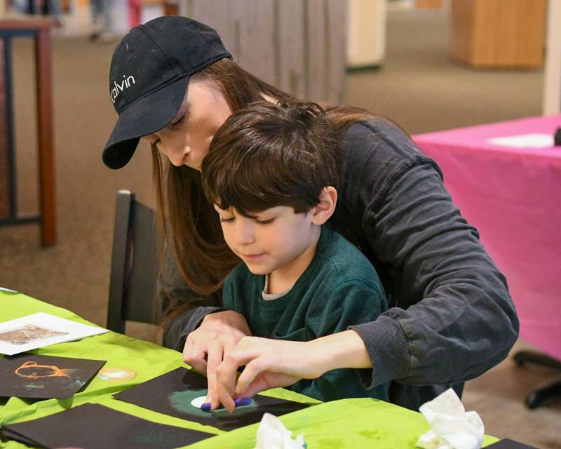 Devyn and her son Francisco Castillo jr. of Glen Ellyn make their own solar eclipse drawing at the Wheaton library with paper, stencil and crayons before the solar eclipse took place on Monday April 8, 2024.