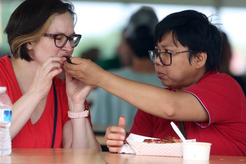 Janice Rusia, right, shares her ribs with Christi Dentro, left, during the Rockin’ Rib Fest Friday at Sunset Park in Lake in the Hills. Both are from Lake in the Hills. Rockin’ Rib Fest is a four-day festival that features live entertainment, a carnival and a variety of award-winning barbecue and rib vendors.