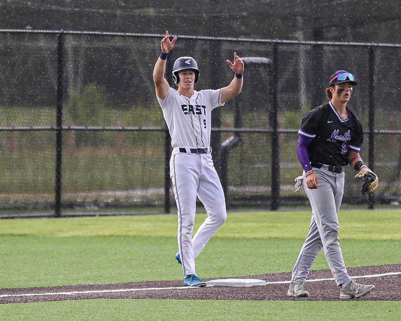 Oswego East's Josh Polubinski (9) signals to the dugout from third base after driving in the game's first runs during Class 4A Romeoville Sectional semifinal between Oswego East at Downers Grove North.  May 31, 2023.