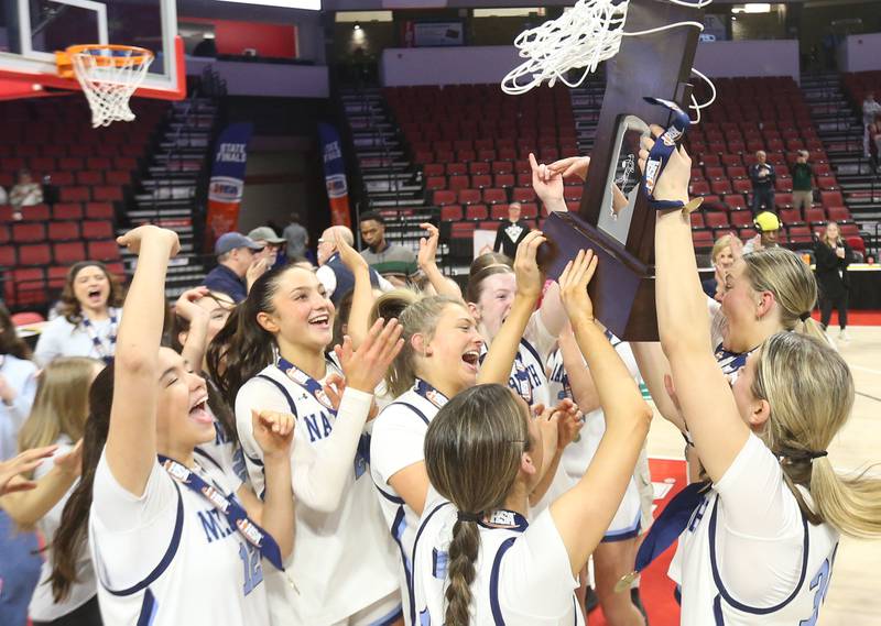 Members of the Nazareth girls basketball team hoist the Class 4A State championship trophy after defeating Loyola on Saturday, March 7, 2026 at CEFCU Arena in Normal.