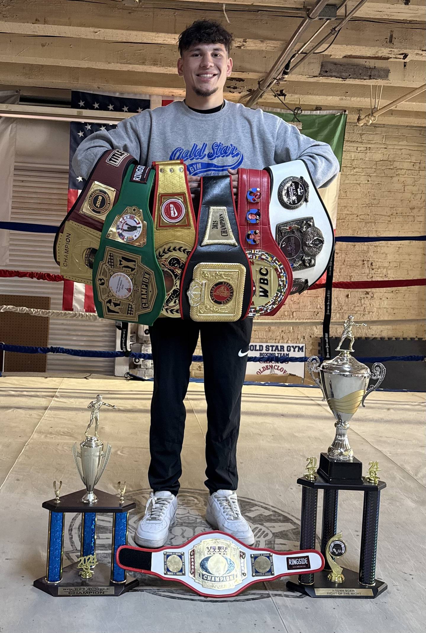 Anthony Mancilla poses with various trophies and belts he has won in his boxing career.