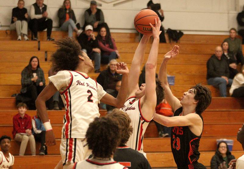 Crystal Lake Central’s Jackson Hopkins, right, battles  Huntley’s Ethan Blackmore, center, and Omare Segarra, left, for the ball during tournament basketball action at Johnsburg High School Monday evening.