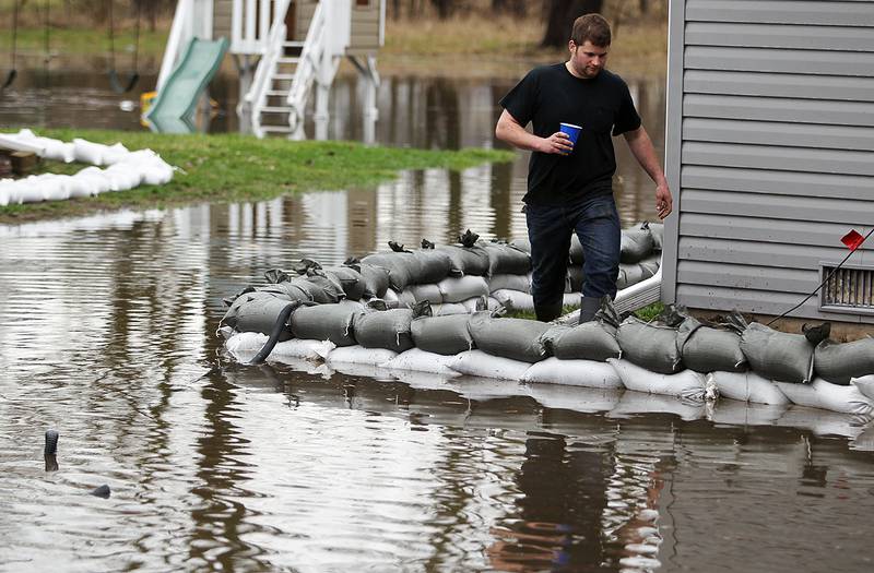 Corbin Turner of Genoa walks around his grandfathers home on West Riverside Drive in McHenry while helping to control the water after the Fox River flooded most of the yard on Thursday, April 19, 2013.