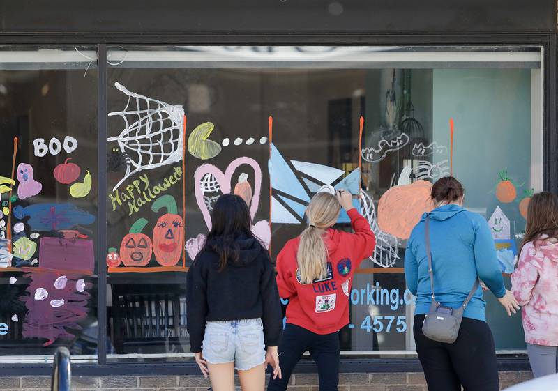 Kids paint Halloween decorations on the windows of local businesses in Downers Grove, Ill. on Saturday, October 22, 2022.