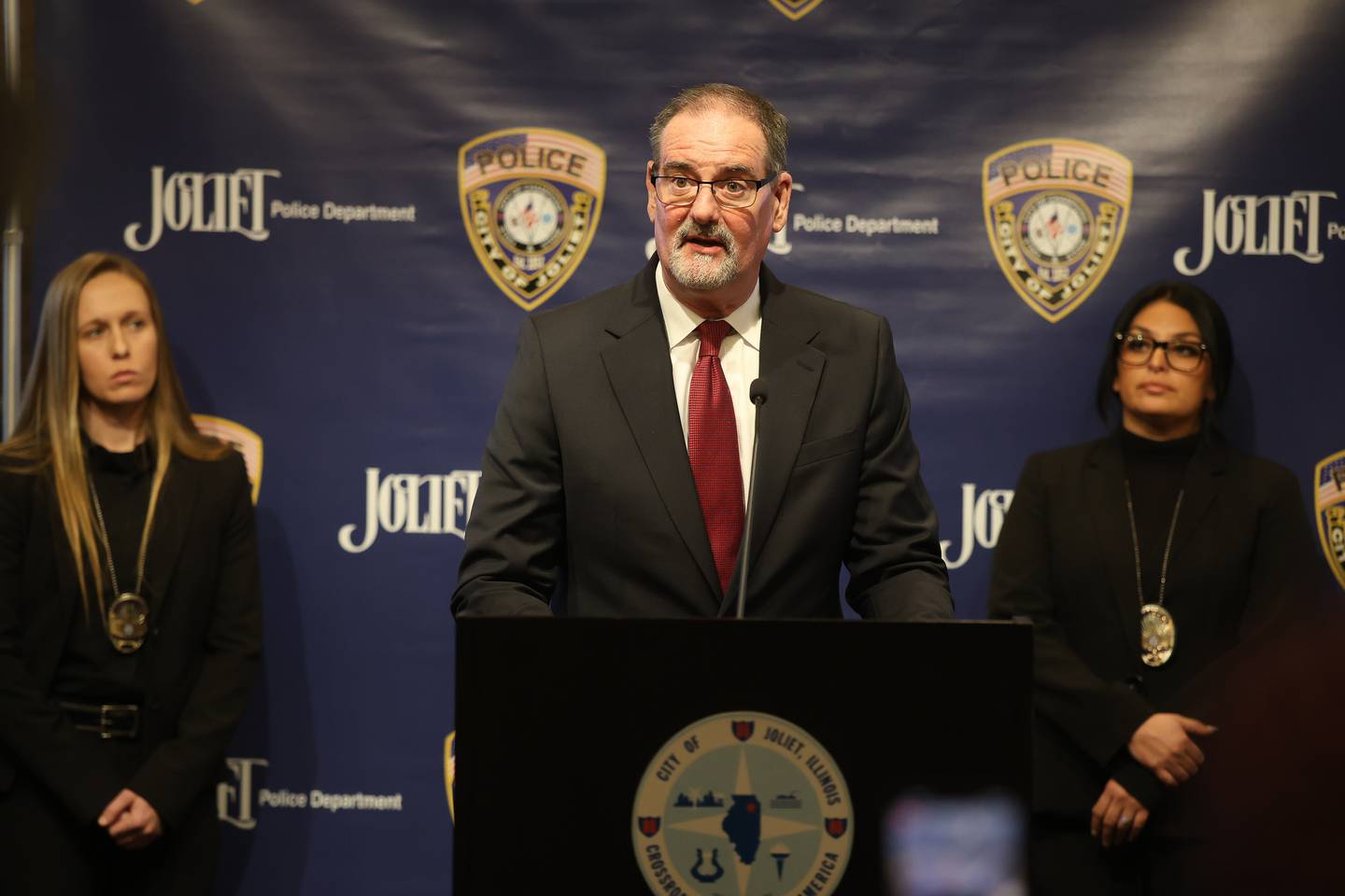 Plainfield School District 202 Superintendent Glenn Wood is flanked by Detective Kristoff Petro and Detective Andrea Espinosa while speaking at a press conference regarding the recent arrest of a former Plainfield School District 202 teacher on multiple charges for alleged inappropriate conduct with a student on Monday, April 20, 2026 in Joliet.