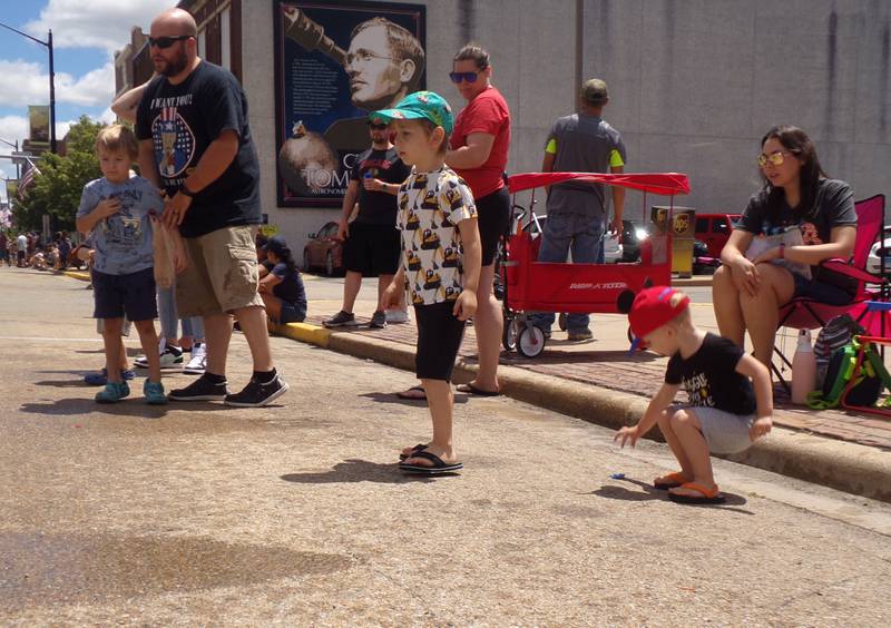 Zachary Holcomb (standing, center) and Maxwell Holcomb (picking up candy) watch alertly for candy Sunday, June 30, 2024, during the Liberty Fest parade in Streator.