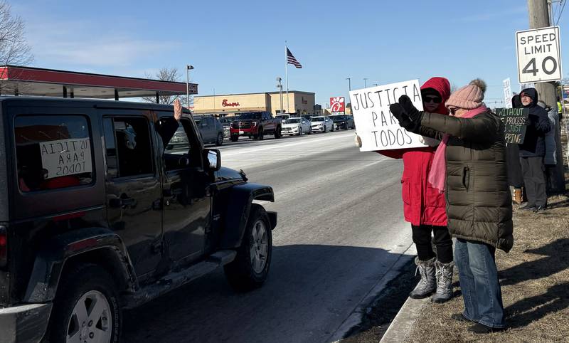 Debbie Groat, left, and Cheryl Reimer wave at a passing car at a protest in McHenry Feb. 1, 2026.