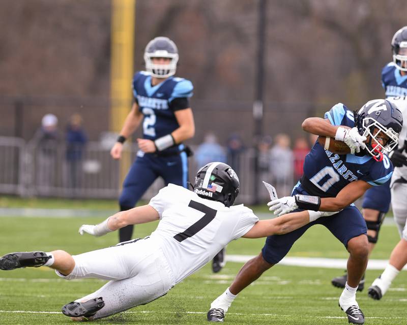 Nazareth Academy's Edward McClain Jr (0) escapes the hands of Fenwick's Tommy Thies (7) to gain some extra yards before being brought down during the 6A semifinals game on Saturday Nov. 22, 2025, held at Nazareth Academy High School in La Grange Park.