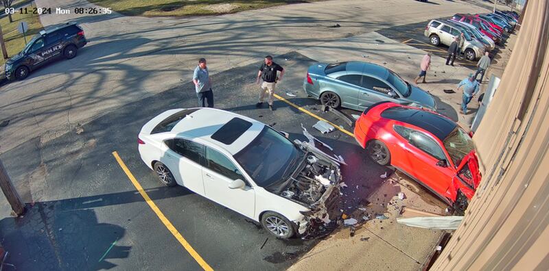 Police said a man driving the red car crashed into a business' building in Harvard, striking the two other cars as well.