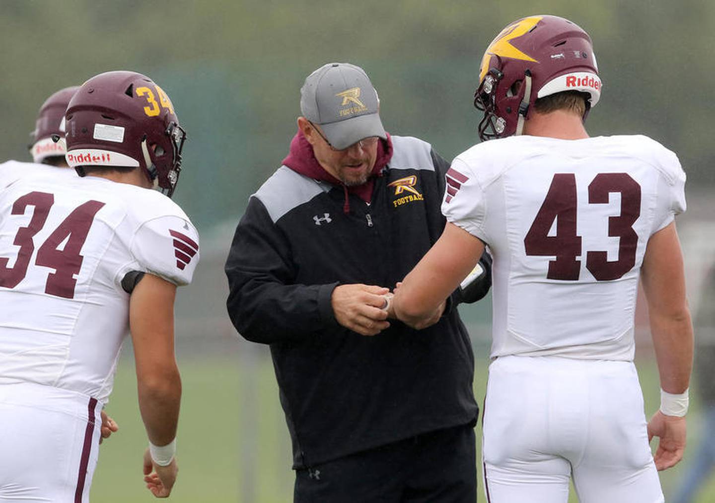 Marengo defensive coordinator Steve Wood, center, tapes Dalton Wood's wrist as Brock Wood, left, heads back for another play while the Indians warm up before facing Richmond-Burton during their week 5 football game at Marengo Community High School on Saturday, Sep. 28, 2019 in Marengo.  The game was originally scheduled for Friday, but rain postponed the game to Saturday.  Richmond-Burton won 38-13.  Steve Wood is Brock's and Dalton's father.